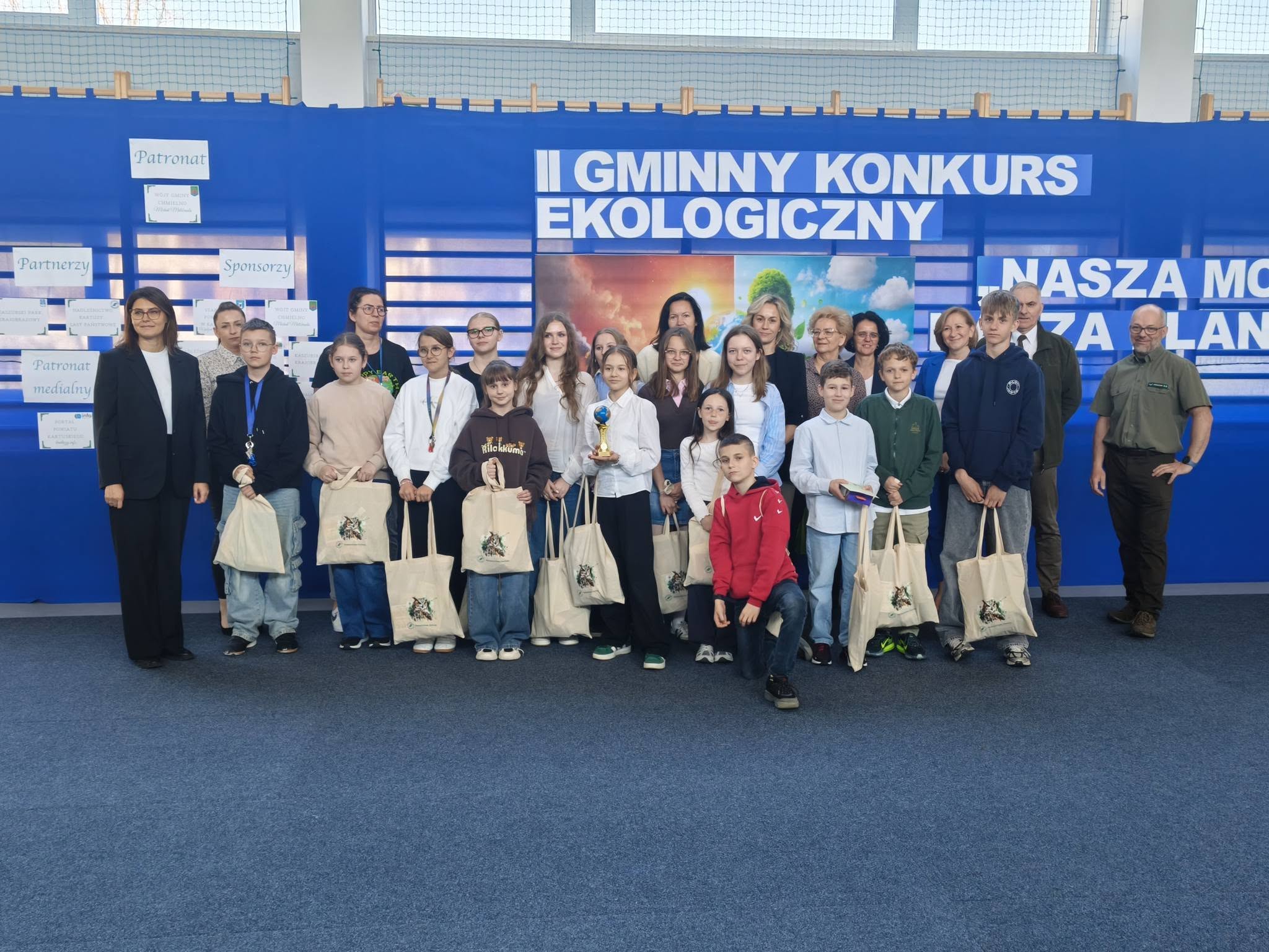 Uczestnicy i organizatorzy pozują do zdjęcia podczas gminnego konkursu ekologicznego.