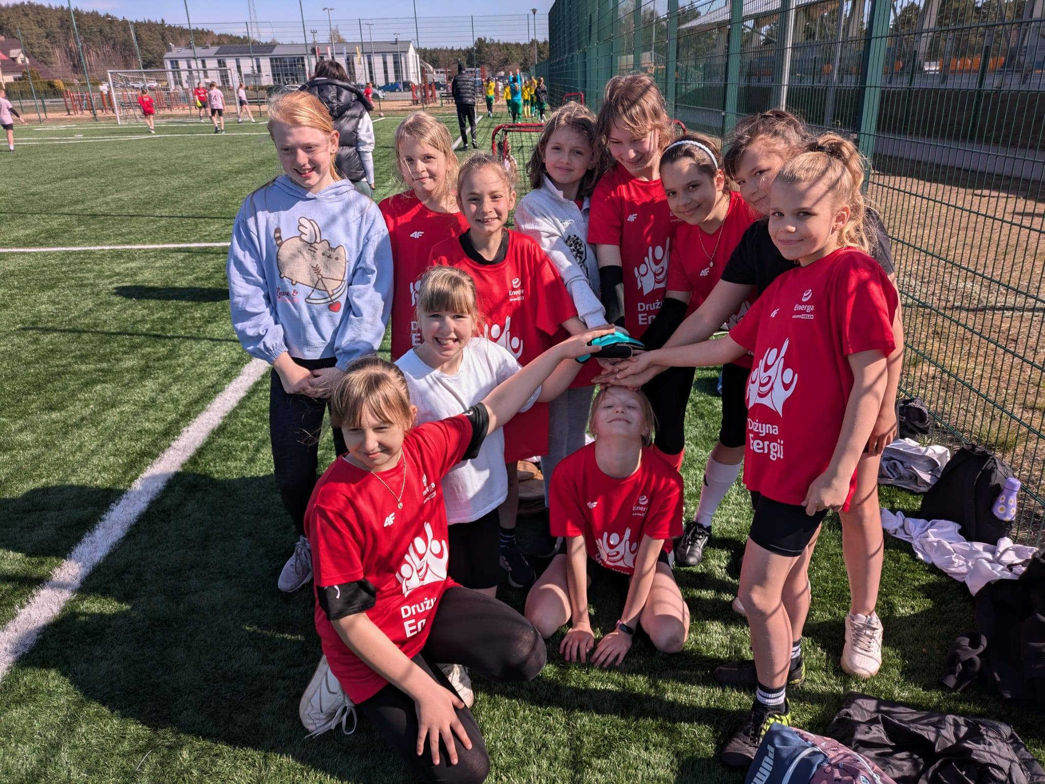 Drużyna dziewcząt pozuje razem na boisku sportowym podczas szkolnych zawodów.