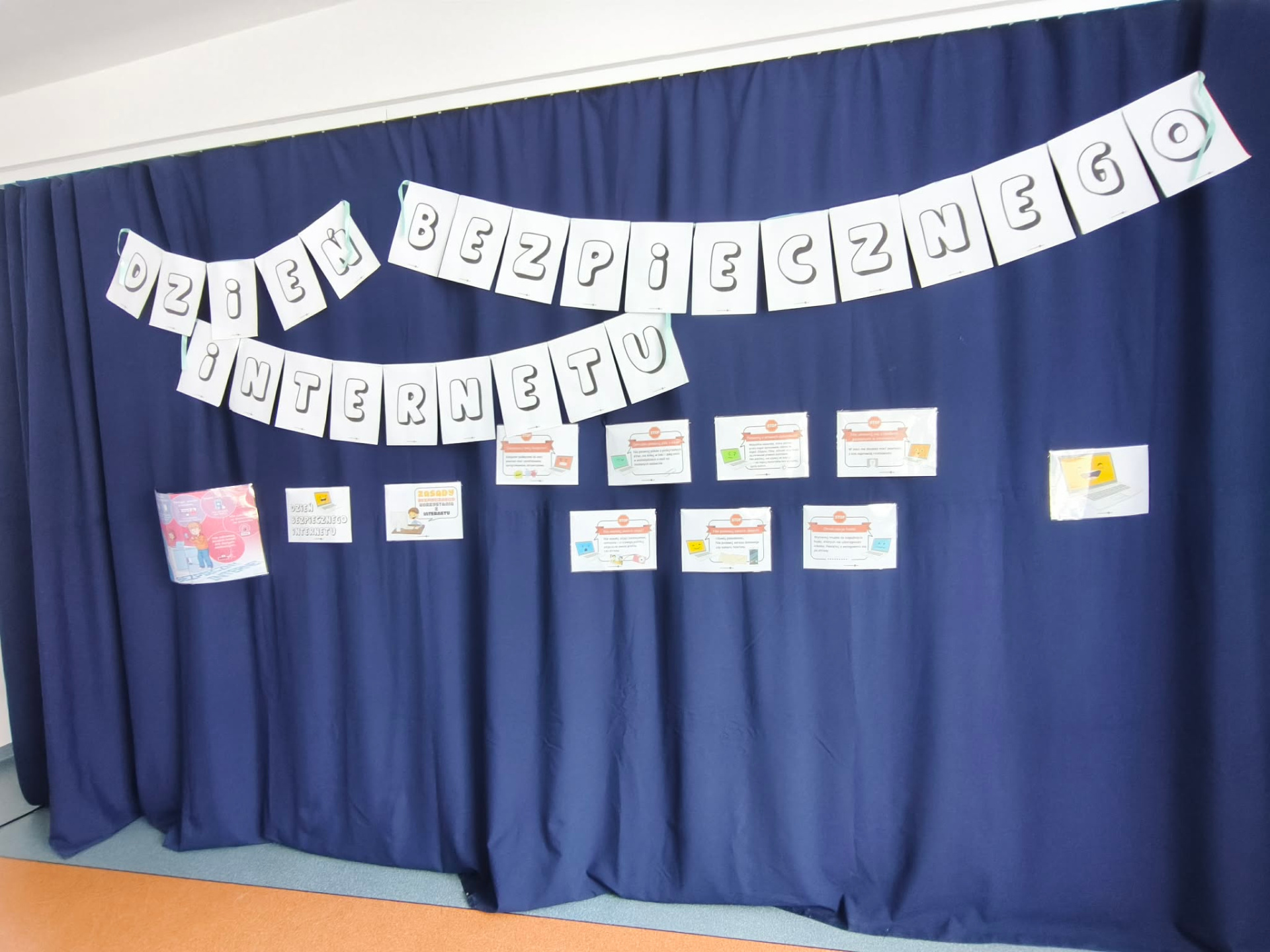 Szkolna gazetka na niebieskim tle z napisem „Dzień Bezpiecznego Internetu”. Pod napisem widnieją edukacyjne ulotki i zasady bezpiecznego korzystania z sieci.