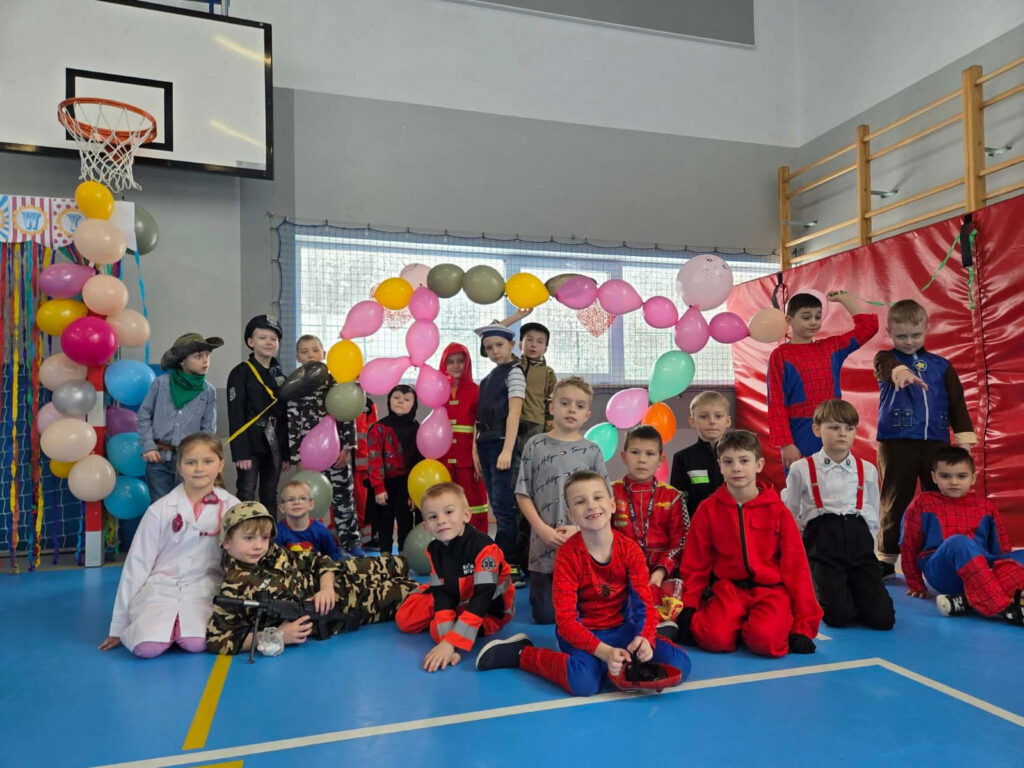 Grupa uczniów w strojach superbohaterów i służb mundurowych pozuje do wspólnego zdjęcia.
