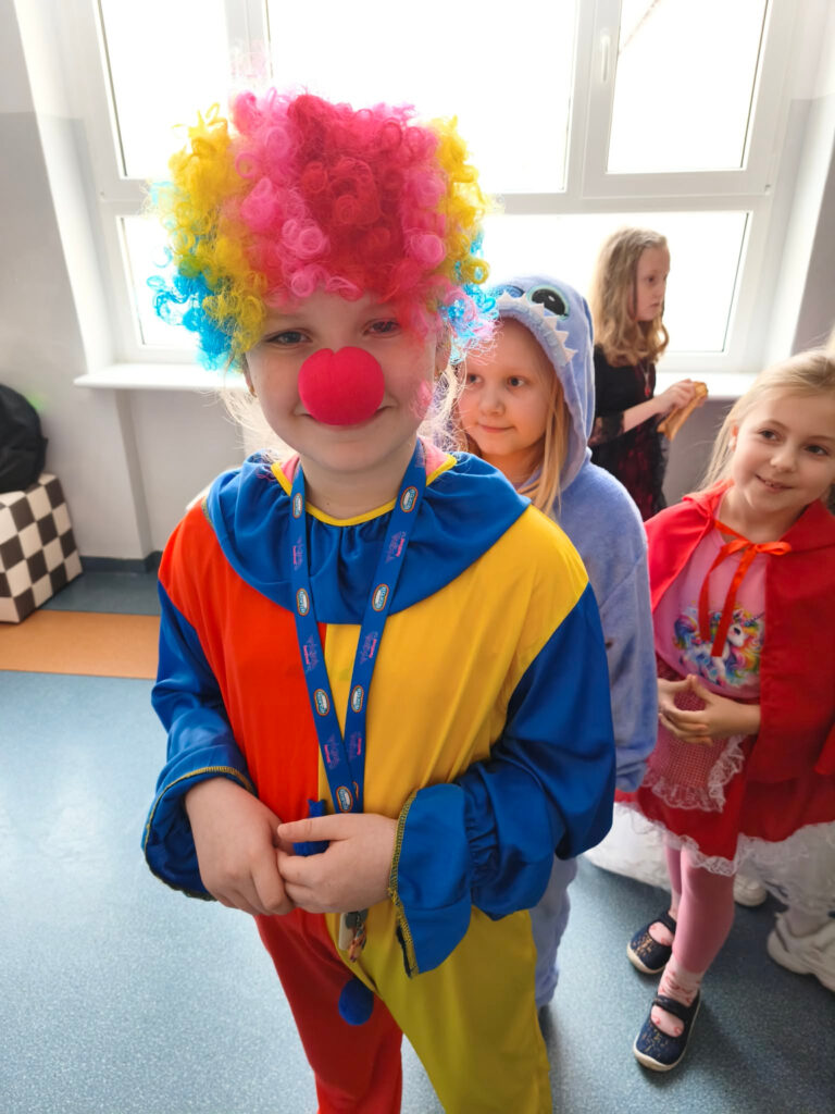 Uczennica przebrana za klauna w kolorowej peruce podczas balu karnawa艂owego.