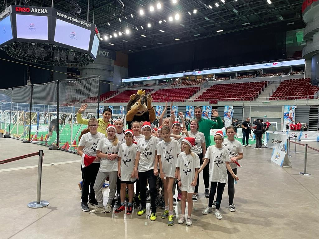 Uśmiechnięciu uczniowie na sali sportowej z maskotką sportową