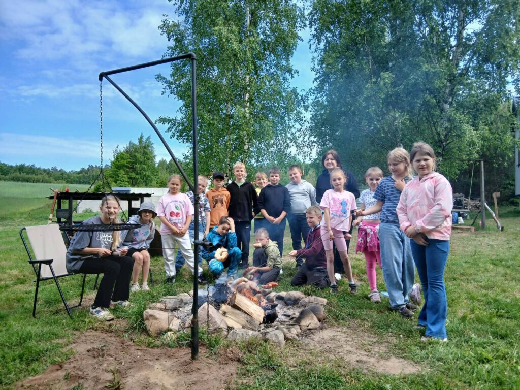 Uczniowie wraz z opiekunem uczestniczą w integracyjnym ognisku podczas wyjazdu edukacyjno-rekreacyjnego na łonie natury.